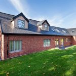 Modern house brick elevation and rear garden in dappled sunlight