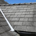 A close up view of a slate roof over a dormer window on a house